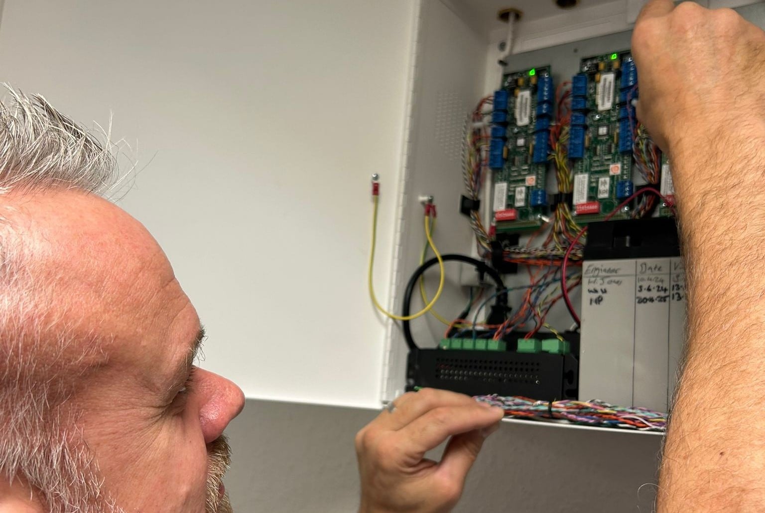 Man working on wiring inside an electrical control panel.