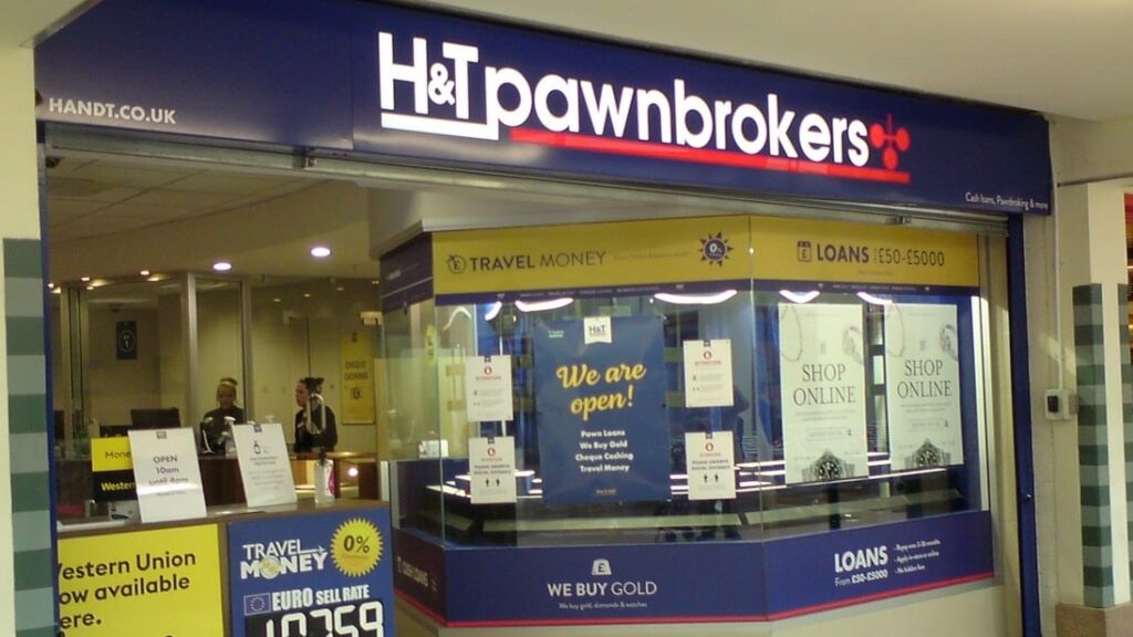 Storefront of H&T Pawnbrokers with signs for loans, travel money, and gold buying.