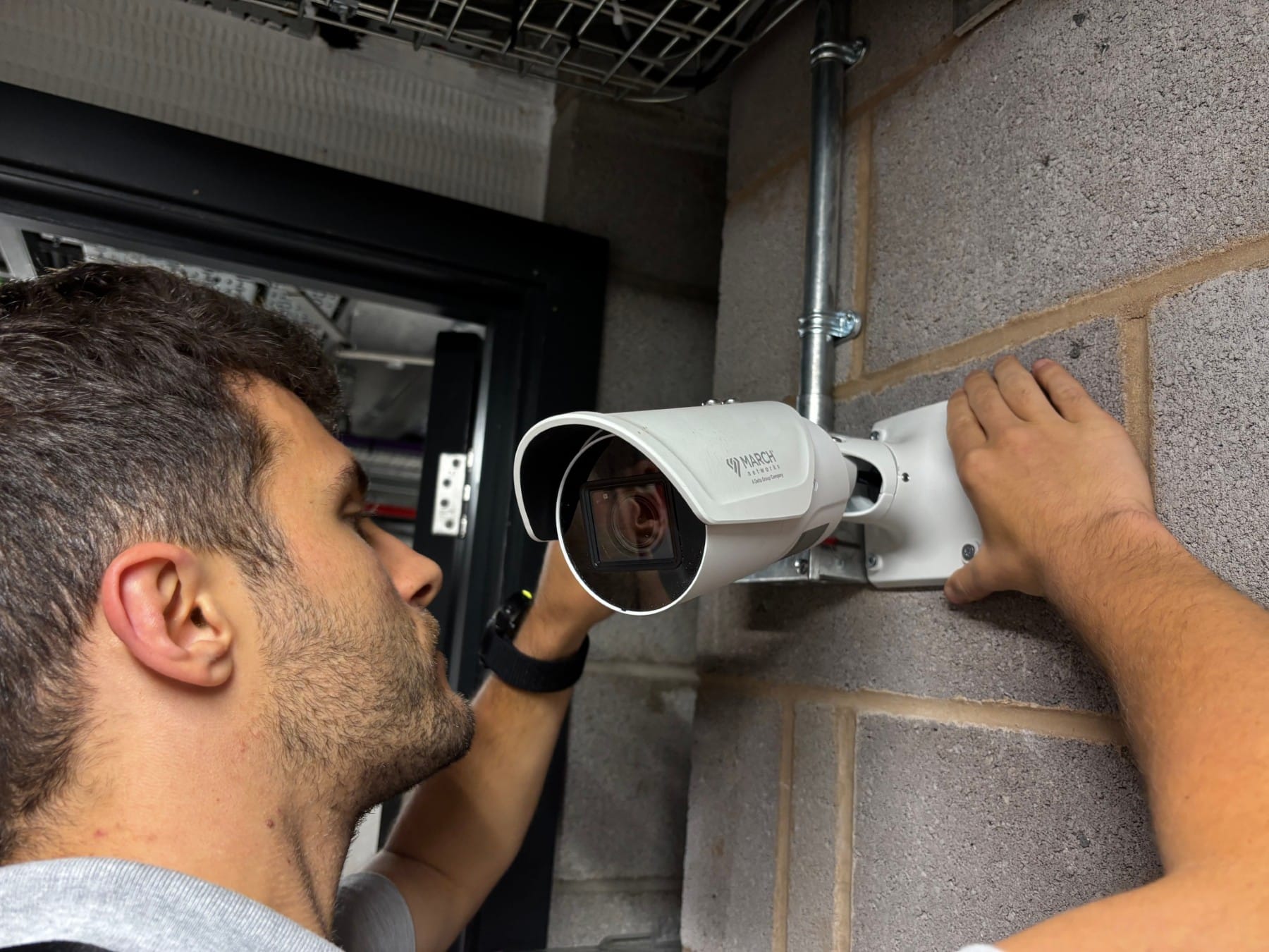 Maintenance - Planned Maintenance A technician installs or adjusts a security camera on a brick wall.