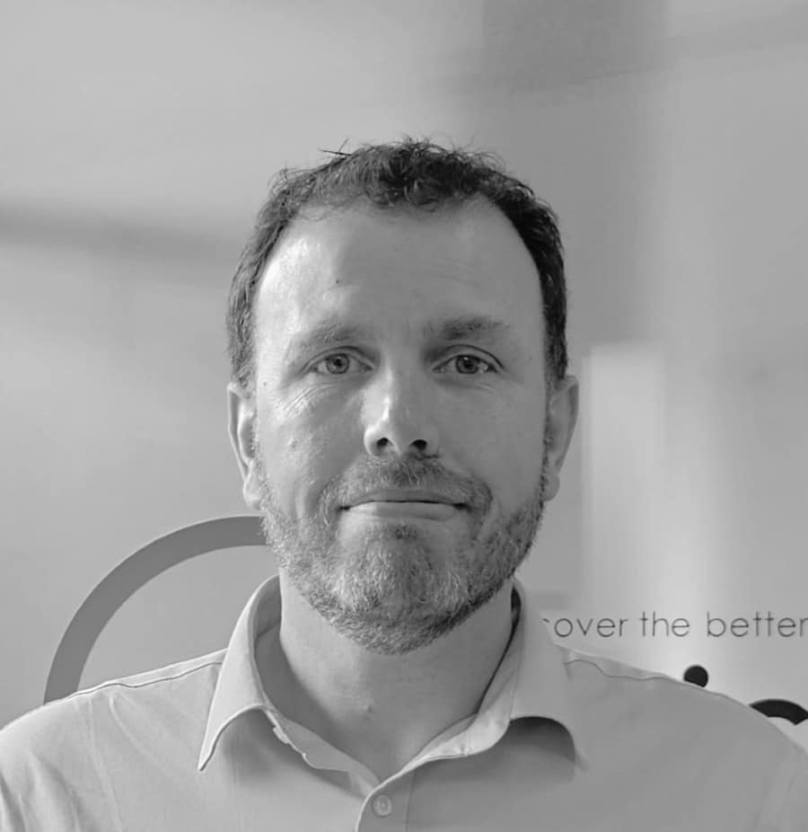 StuartVaughan Man with short hair and beard wearing a collared shirt, photographed in black and white, facing forward.