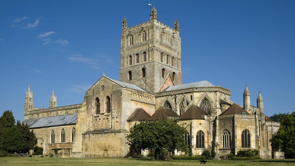 Large stone abbey with a tall central tower under a clear blue sky.