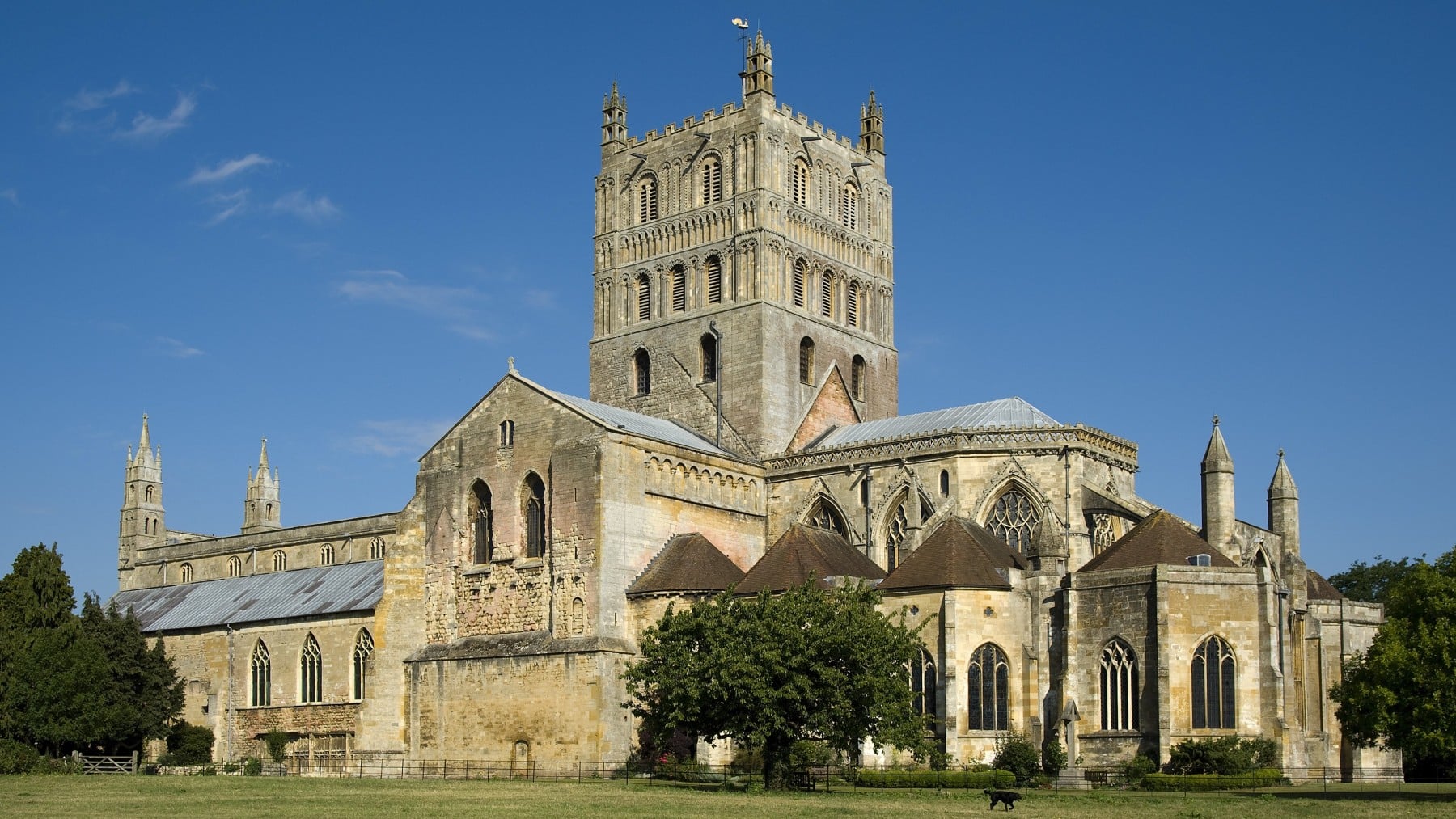 Large stone abbey with a tall central tower under a clear blue sky.